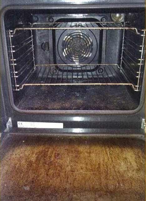 Oven interior before professional cleaning: baked-on grease on the door glass, racks and cavity floor